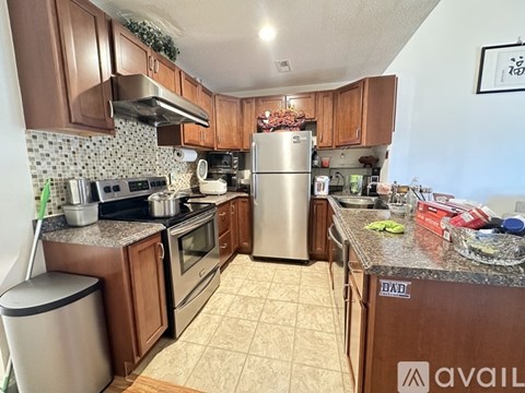 A kitchen with brown cabinets and a stainless steel refrigerator.