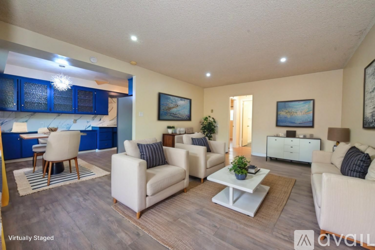 A living room with a white couch, a coffee table, and a dining table with chairs.