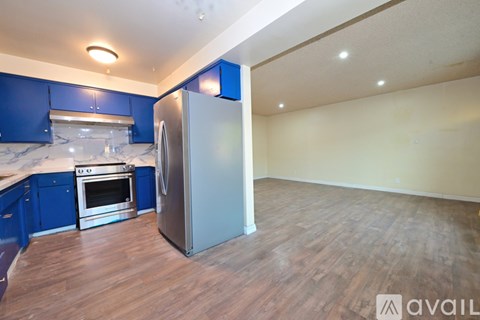 A kitchen with blue cabinets and a stainless steel refrigerator.