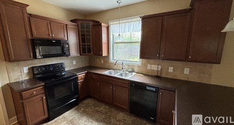 A kitchen with brown cabinets and black appliances is available for rent.