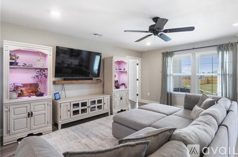 A living room with a grey sofa and a television on the wall.