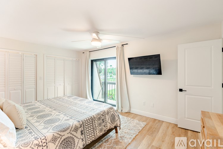 A bedroom with a bed, a ceiling fan, and a window with curtains.