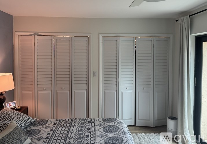 A bedroom with a bed, a lamp, and a fan.