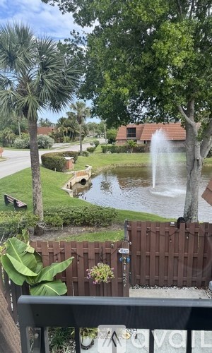 A fountain in the middle of a pond surrounded by trees.