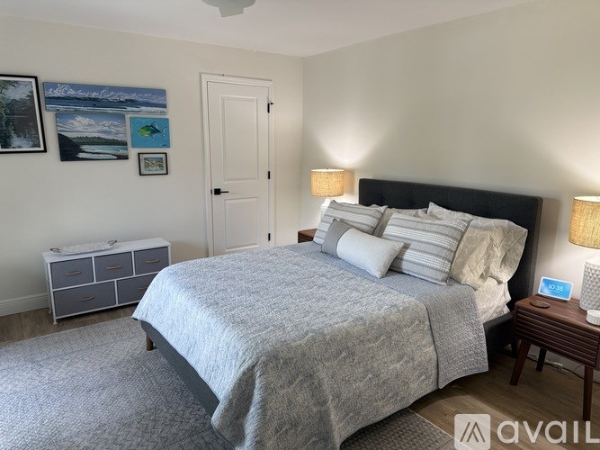 A bedroom with a large bed and a nightstand with a lamp.