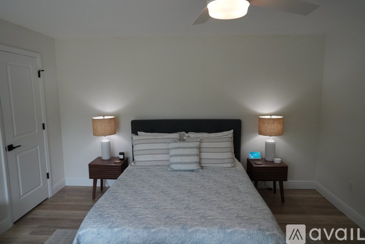 A bedroom with a bed, two lamps, and a ceiling fan.