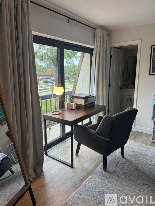 A table with a book on it and a chair in front of a sliding glass door.