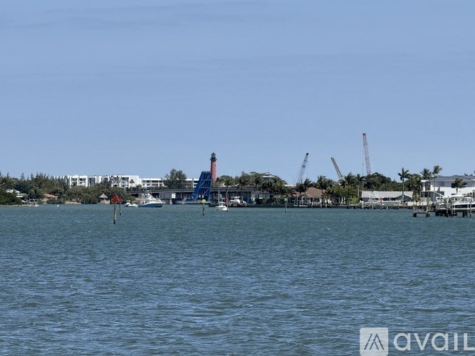 A lighthouse stands in the distance on a clear day over a body of water.