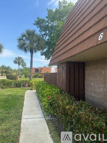 A sign for Jupiter Plantation stands in front of a lush green backdrop.