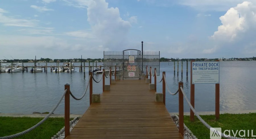 A wooden dock leads to a private dock with a sign.
