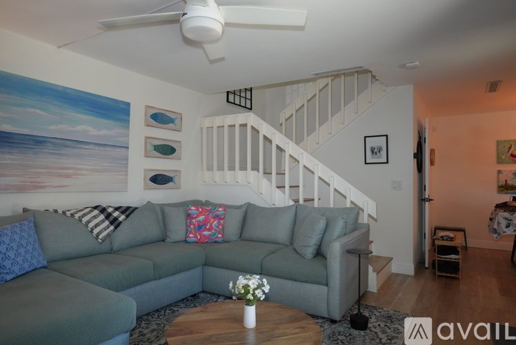 A living room with a grey couch and a painting of the sea on the wall.