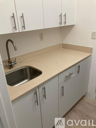 A kitchen with white cabinets and a beige countertop.