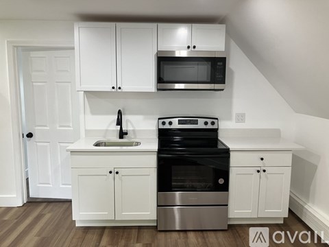 A kitchen with white cabinets and a black microwave above the stove.