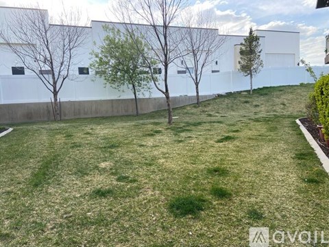 A grassy area in front of a white building with trees.