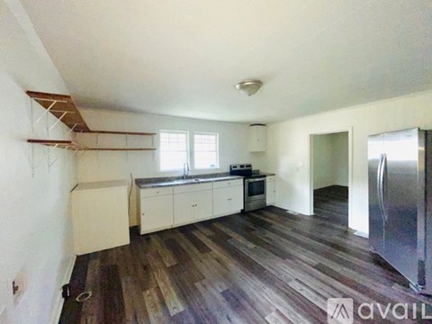 A kitchen with white cabinets and a wooden floor.