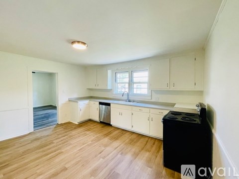 A kitchen with white cabinets and a black trash bin.