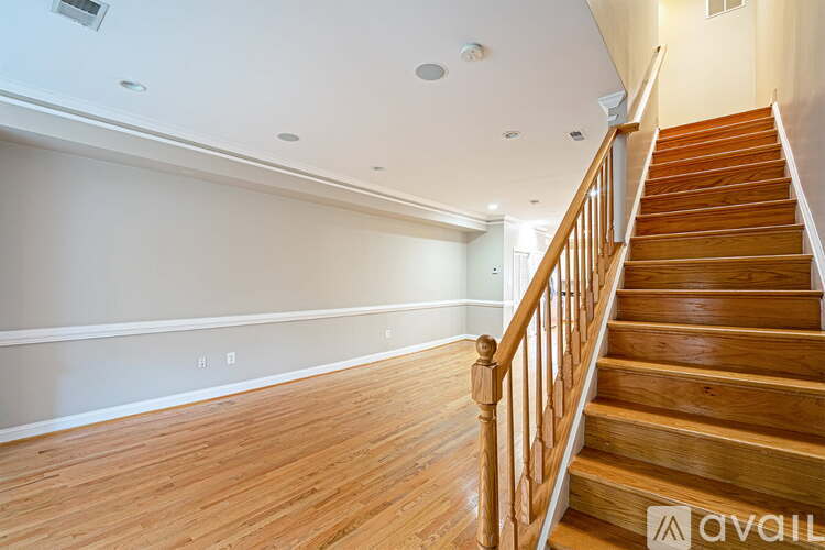 A wooden staircase with a railing leads up to a brightly lit second floor.