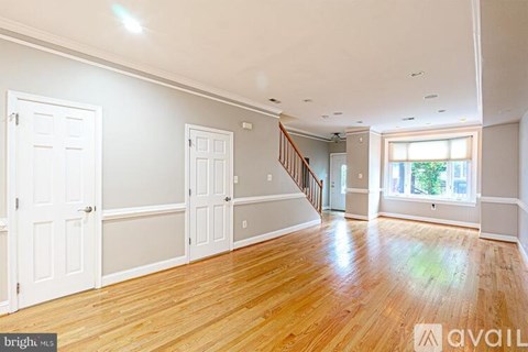 A wooden staircase with a railing leads up to a brightly lit second floor.