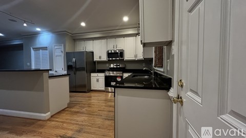A kitchen with a black fridge and stove top oven.