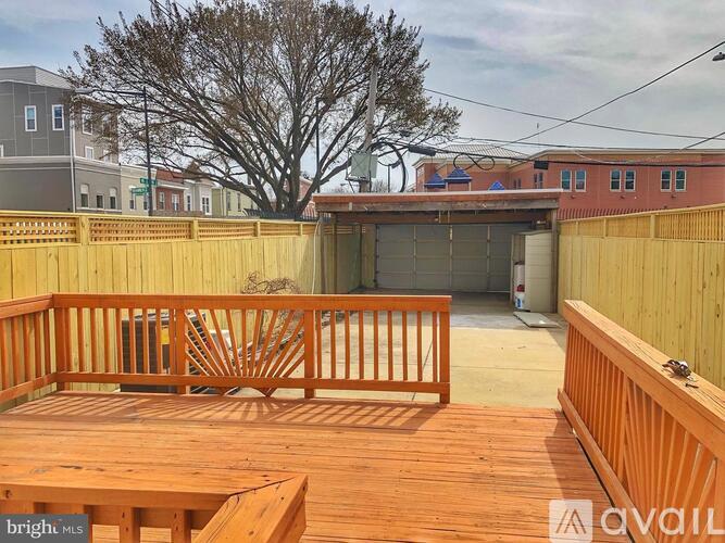 A wooden deck with a table and chairs in the foreground and a building in the background.