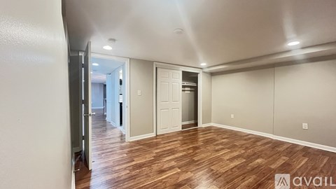 A spacious room with wooden flooring and white walls.