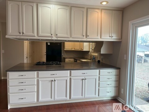 A kitchen with white cabinets and a black stove top.