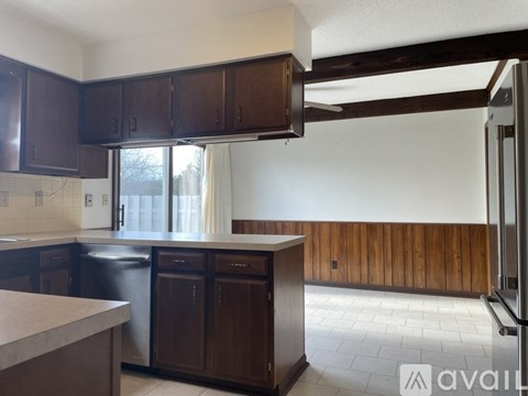 A kitchen with dark brown cabinets and a black fridge.