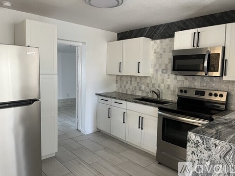 A kitchen with a refrigerator, microwave, oven, and cabinets.