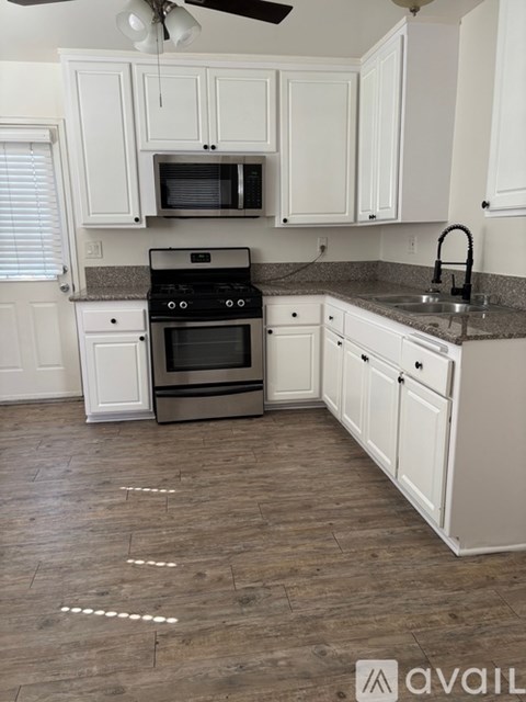 A kitchen with white cabinets and a black stove top oven.
