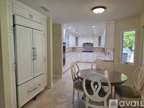 A kitchen with a table and chairs in the foreground and a refrigerator to the left.