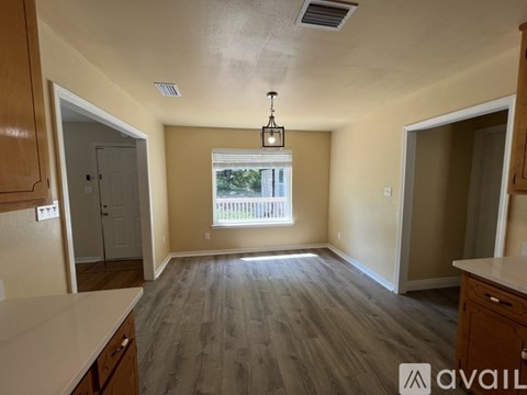 A room with wooden floors and a window with a view of trees.