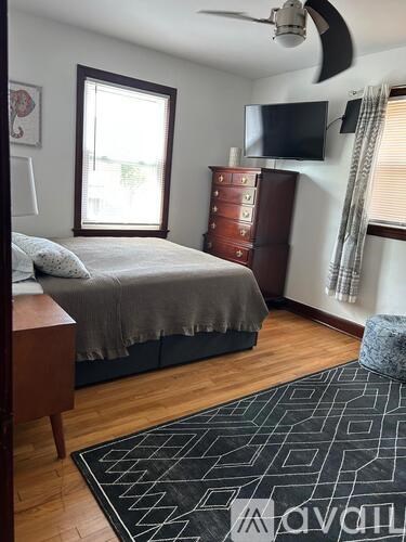 A bedroom with a bed, a dresser, and a ceiling fan.