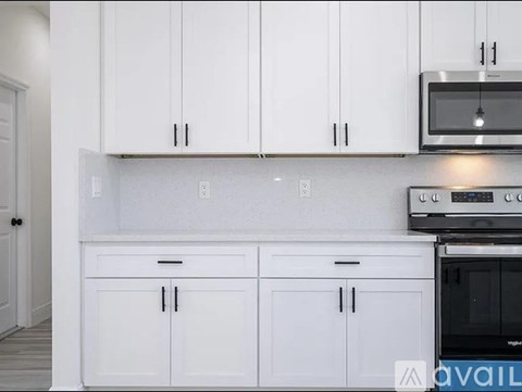 A kitchen with white cabinets and a black microwave.