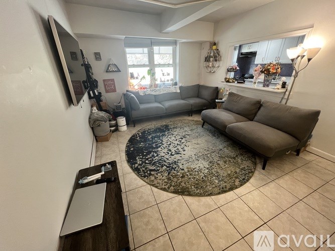 A living room with a grey couch and a rug.