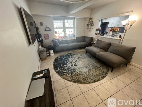 A living room with a grey couch and a rug.