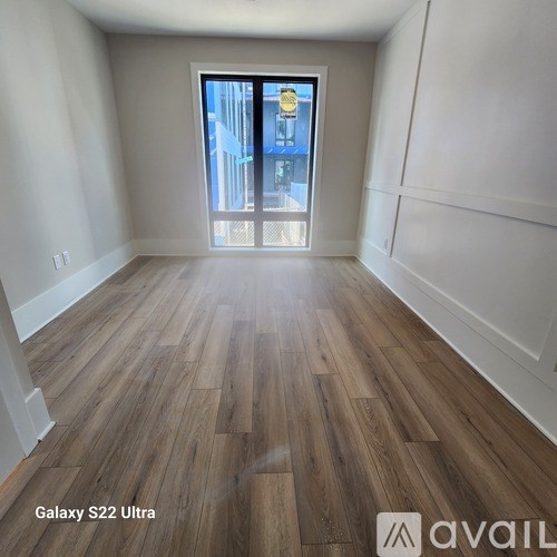 A room with wooden flooring and a doorway leading to a balcony.