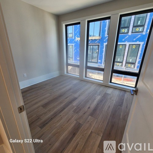 A room with wooden flooring and three windows.