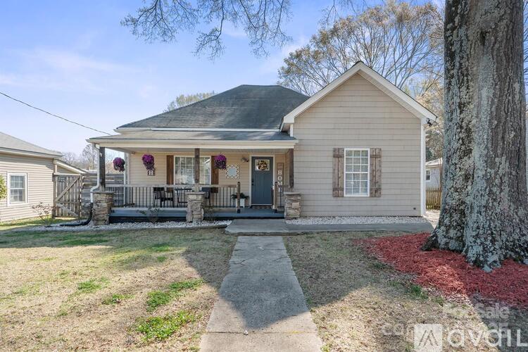 A small house with a front porch and a tree in front.