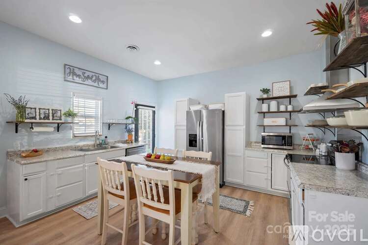 A kitchen with a table set for two and a fridge to the side.