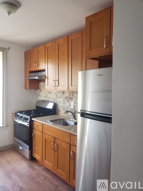 A kitchen with wooden cabinets and a stainless steel refrigerator.