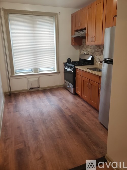 A kitchen with wooden floors and a window with blinds.