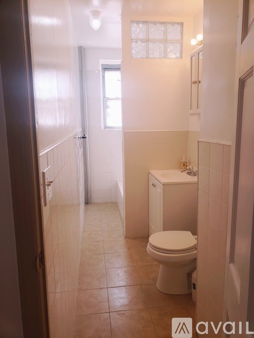 A white toilet in a small bathroom with tiled floors and walls.