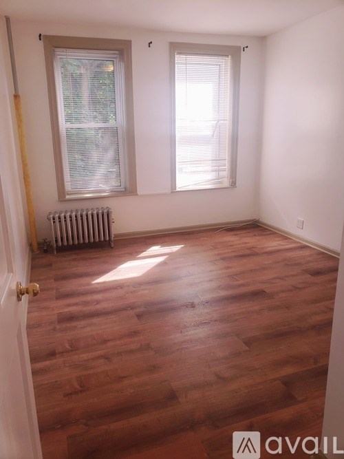 A room with wooden floors and a window with blinds.