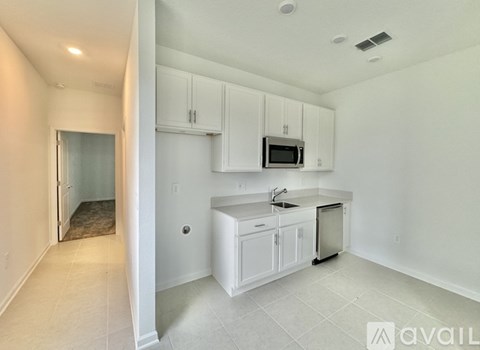 A kitchen with white cabinets and a microwave above the sink.