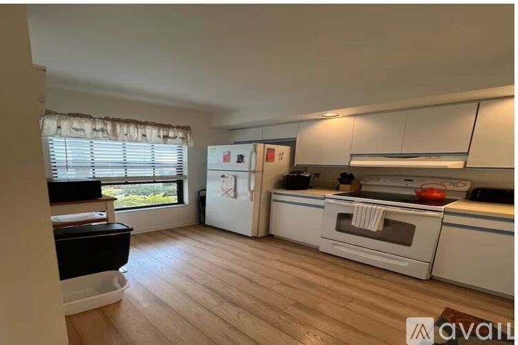 A kitchen with white appliances and wooden floors.