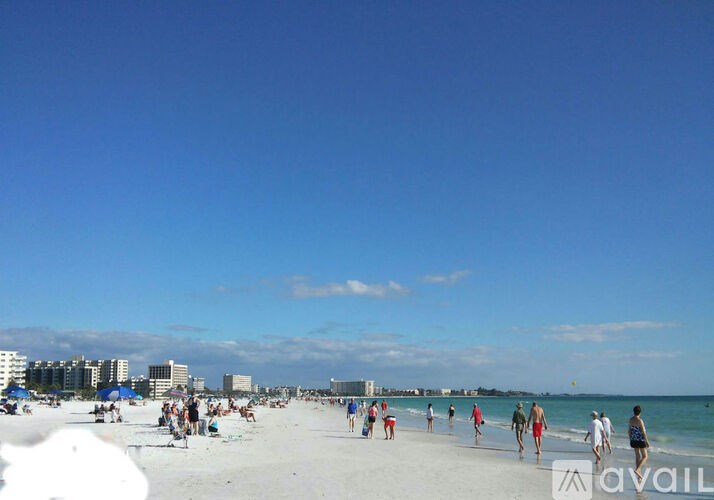 A beach scene with people walking and playing on the sand.