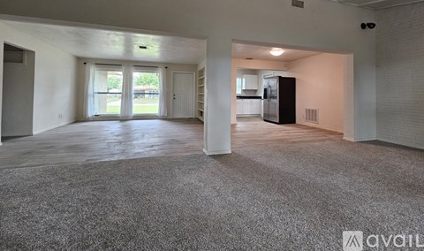 A spacious living room with a grey carpet and white walls.