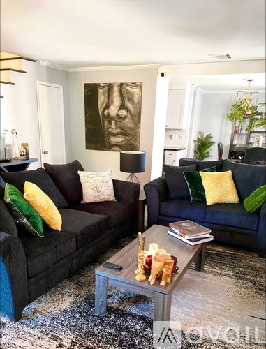 A living room with a black couch and a coffee table with a book and a small statue on it.