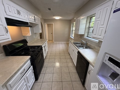 A kitchen with white cabinets and black appliances.