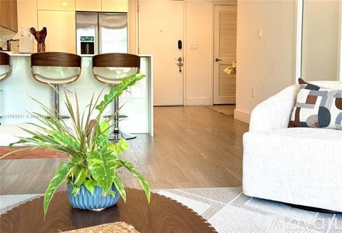 A living room with a white couch and a plant in a blue vase.